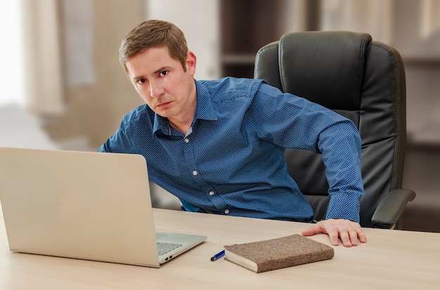 Un jefe serio en su escritorio mira la pantalla de una computadora portátil. Empleado de oficina. Gerente de departamento.
