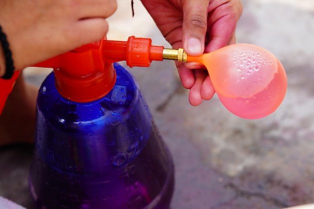 Jemand füllt Wasser in den Ballon für Holi