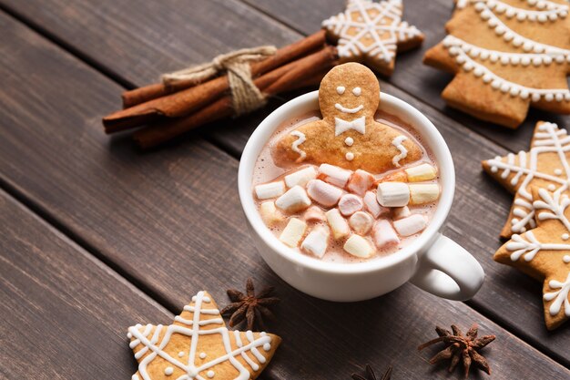 Jengibre dulce en taza de chocolate caliente con malvaviscos en la mesa de madera