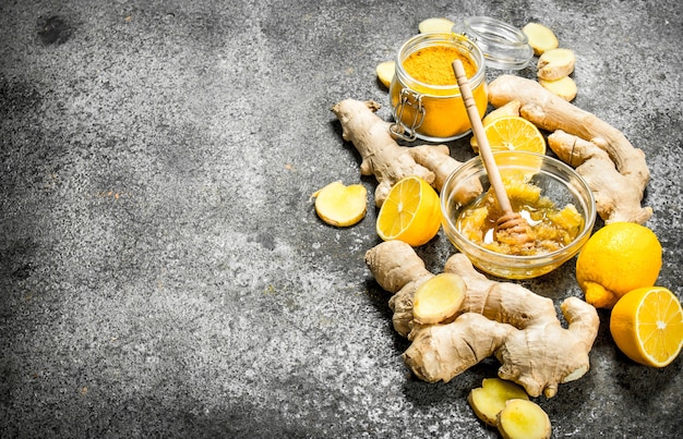 Jengibre fresco con miel y rodajas de limón sobre mesa rústica.