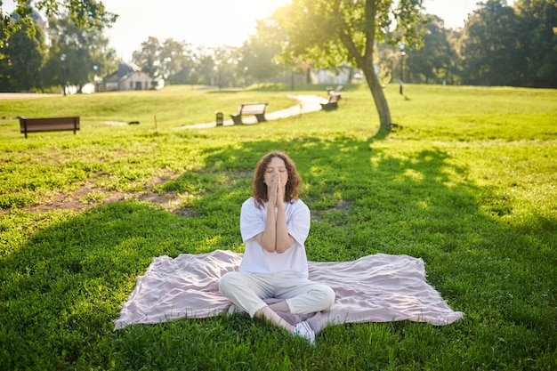 Un jengibre joven meditando en el parque y mirando en paz.