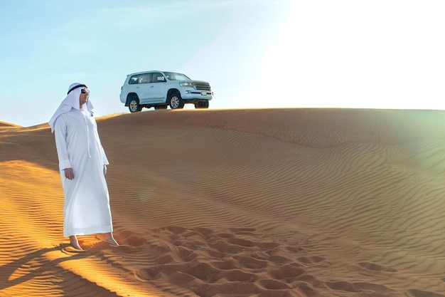 Jeque árabe con un largo vestido blanco en medio del desierto de Dubái