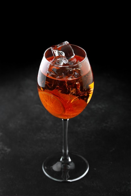 Jeringa de cóctel aperol con hielo sobre un fondo negro