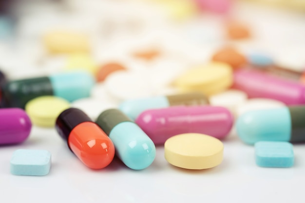 Foto jeringa hipodérmica y frasco de pastillas derramándose. cápsula de píldoras de colores en tabletas de superficie sobre un fondo de madera de mesa.