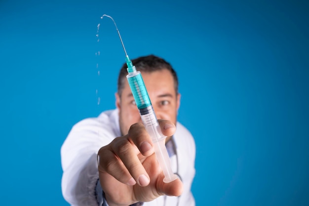 Jeringa de primer plano liberando medicación con un médico detrás del divertido concepto de vacunación