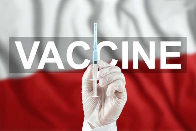 Una jeringa con una vacuna en la mano del médico en el contexto de la bandera de Polonia. Virus corona COVID-19, protección inmunológica, tratamiento contra la infección por nCoV 2019, vacunación.