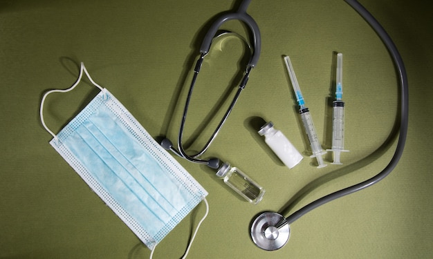 Jeringas, viales, estetoscopio y mascarillas médicas. concepto de vacunacion