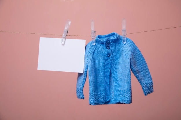 Jersey de punto para bebé y tarjeta en blanco colgando de un tendedero