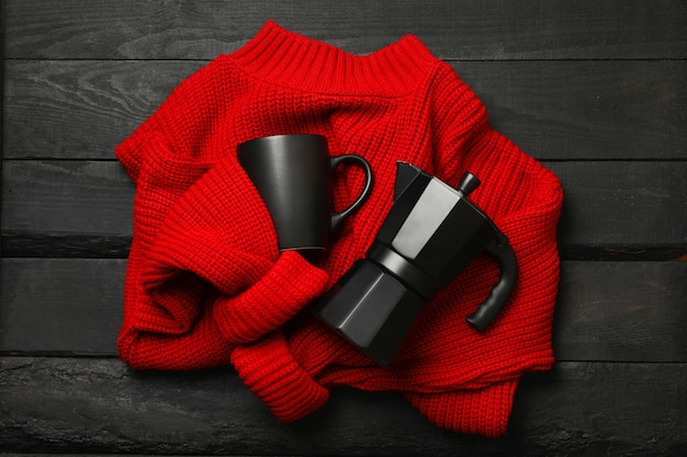 Jersey rojo con cafetera y taza sobre fondo de madera