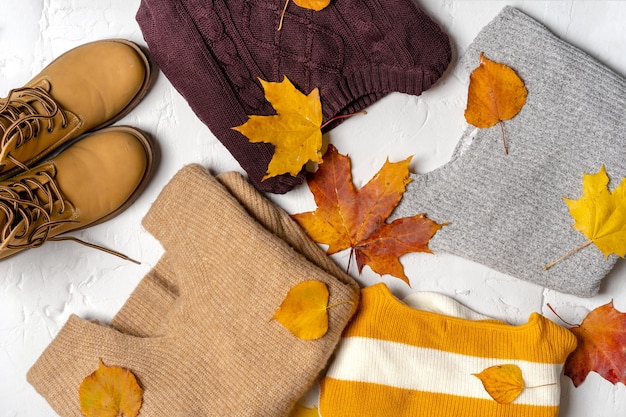 Jerseys y botas de mujer con hojas de arce otoñal.