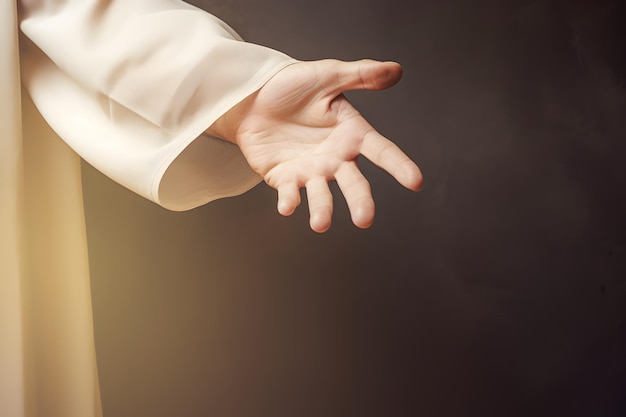 Foto jesucristo extendiendo su mano contra un fondo oscuro