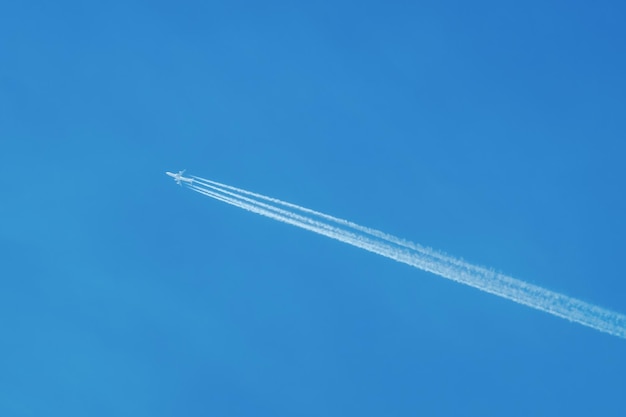 Jet Airliner fliegt hoch in den Himmel und hinterlässt Kondensstreifen am klaren blauen Himmel