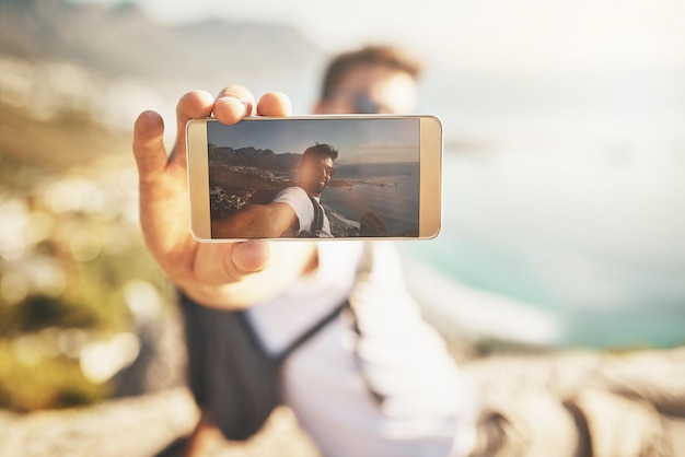 Jetzt kann niemand sagen, dass ich es nie geschafft habe Schnappschuss eines gutaussehenden jungen Mannes, der beim Wandern in den Bergen Selfies macht