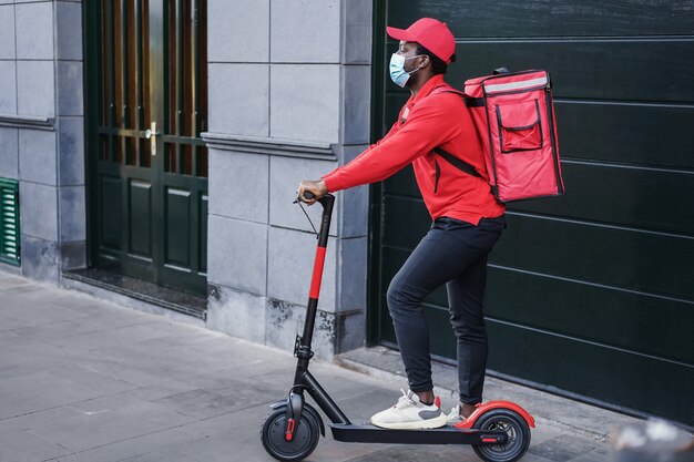 Jinete africano entregando comida con scooter eléctrico - Centrarse en la cara