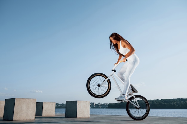 Jinete femenino está en la bicicleta durante el día cerca del lago