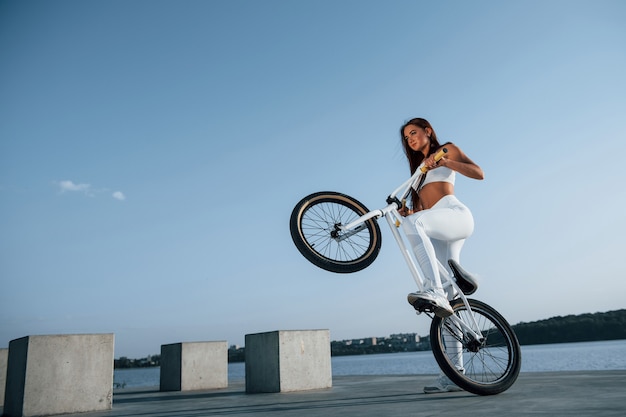 Jinete femenino está en la bicicleta durante el día cerca del lago