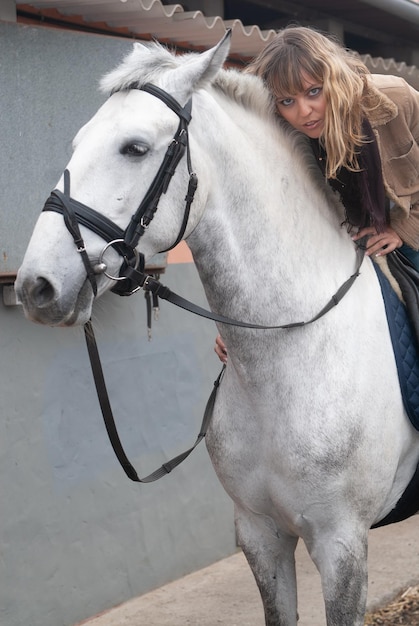 Jinete femenino en los establos montado a caballo antes de salir a correr