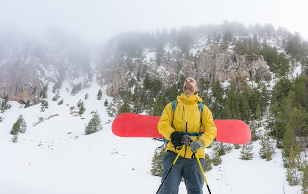 Jinete libre que sube la montaña con su tabla de snowboard