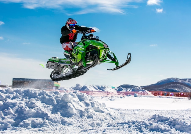 Jinete de motos de nieve saltando a través de la nieve.