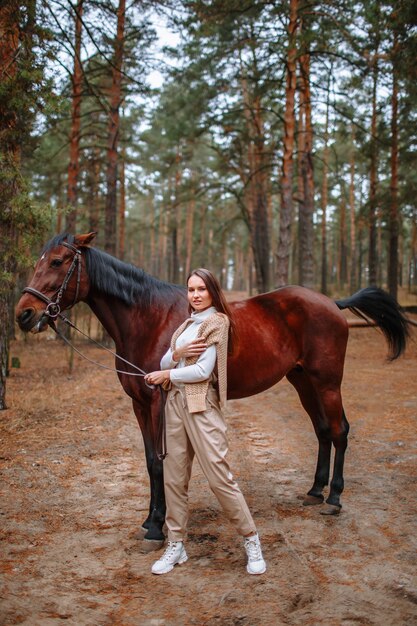 Jinete de niña de pie junto al caballo