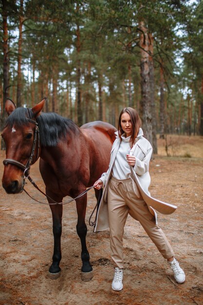 Jinete de niña de pie junto al caballo