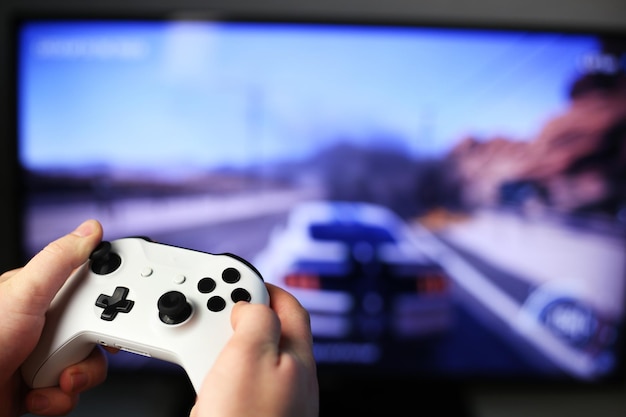 Joga jogos de corrida na TV enquanto segura o gamepad branco