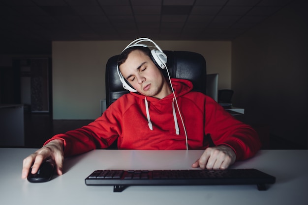 Jogador adormecido em casa no computador. Jovem dormindo em casa jogando