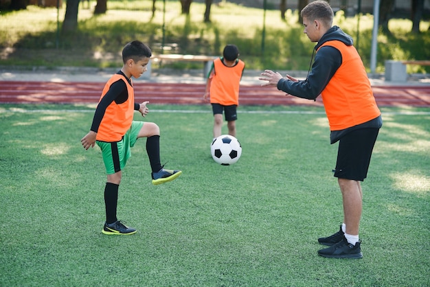 Jogador com uniforme de futebol malhando para chutar a bola com o técnico no estádio