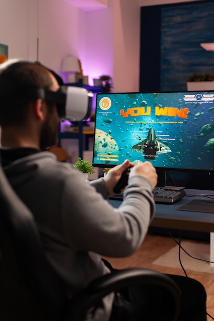 Jogador competitivo usando joystick profissional, jogando jogo de tiro online tarde da noite com fone de ouvido vr. ciber streaming online virtual durante o torneio de jogo ao vivo