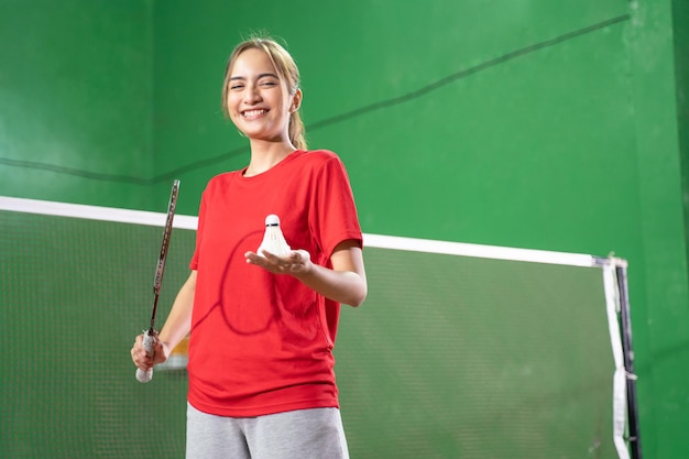 Jogador de badminton feminino sorridente segurando raquete e peteca