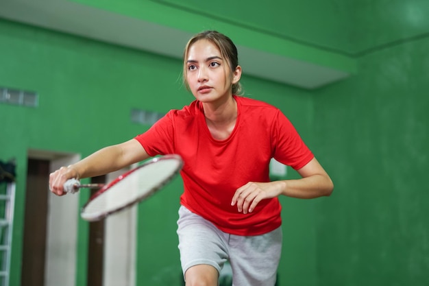 Jogador de badminton segurando raquete em posição pronta na quadra