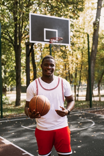 Jogador de basquete afro-americano em um campo de esportes ao ar livre, jogando com uma bola. praticando esportes na rua.