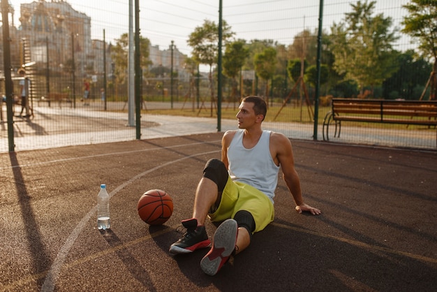 Foto jogador de basquete bebe água em quadra ao ar livre