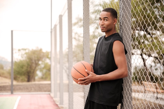 Jogador de basquete em pé no parque enquanto segura o basquete