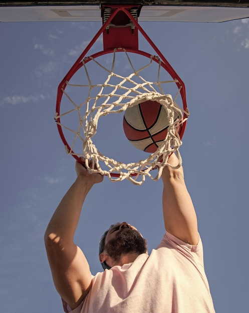 Jogador de basquete joga a bola no aro ao ar livre basquete masculino