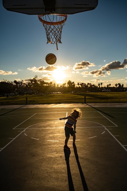 Jogador de basquete para crianças, esporte para crianças, silhueta no pôr do sol