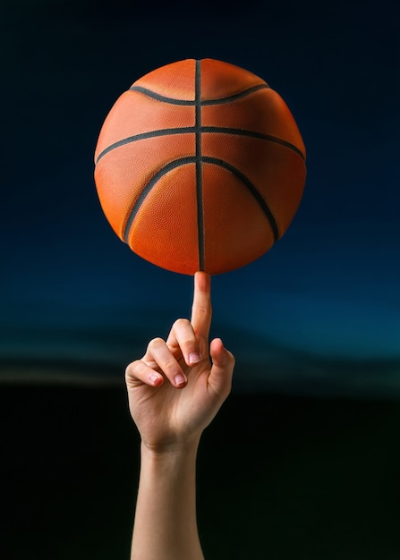 Jogador de basquete profissional girando uma bola no dedo da mão.