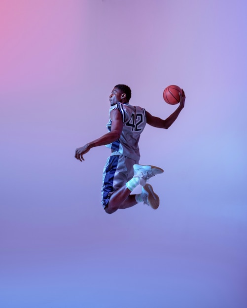 Foto jogador de basquete pulando com a bola. baller profissional masculino em roupas esportivas, jogando esporte, esportista alto