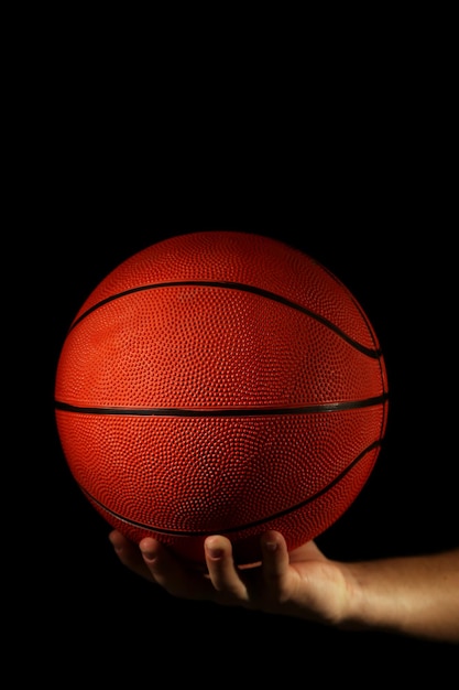 Jogador de basquete segurando uma bola em fundo escuro