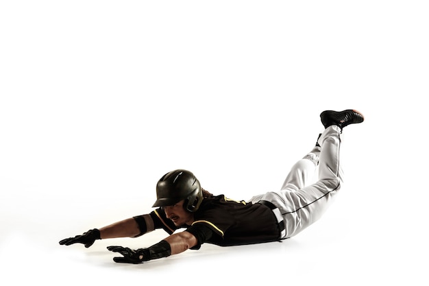 Foto jogador de beisebol, lançador de uniforme preto, praticando e treinando isolado em uma parede branca. jovem desportista profissional em ação e movimento. estilo de vida saudável, esporte, conceito de movimento.