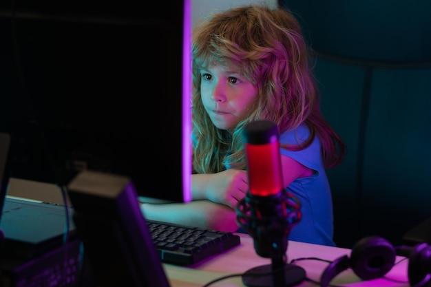 Jogador de criança pequena joga jogo de computador na área de trabalho Fluxo de jogos e blogs para crianças Estudo escolar conceito de aprendizado on-line