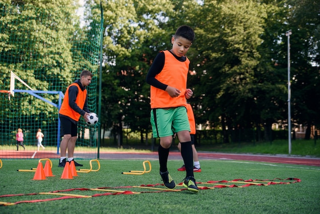 Jogador de futebol adolescente executando exercícios de escada na grama durante o treinamento de futebol