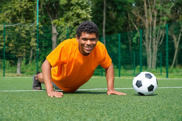 Jogador de futebol afro-americano se aquece para treinar no campo esportivo no verão