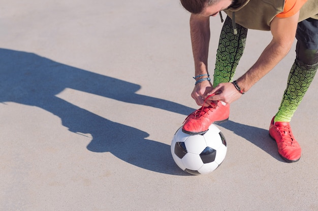 Jogador de futebol amarra suas chuteiras prontas para jogar na