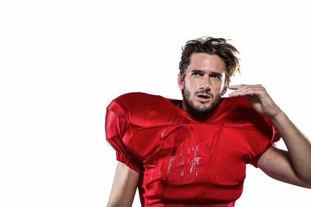 Jogador de futebol americano molhado em jersey vermelho desviando o olhar