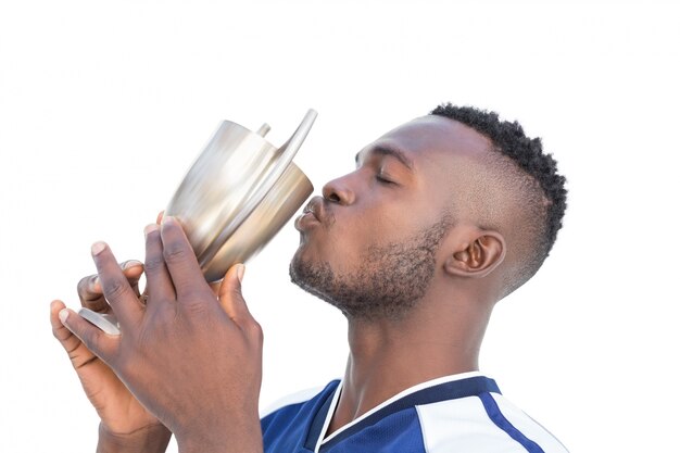 Jogador de futebol beijando o copo dos vencedores