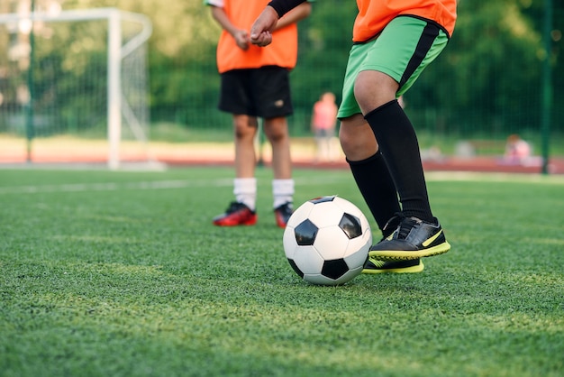 Jogador de futebol chutando a bola no campo. Jogadores de futebol na sessão de treinamento. Feche os pés do jogador de futebol