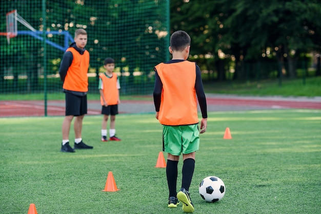 Jogadores de futebol adolescentes chutando bola de futebol campo