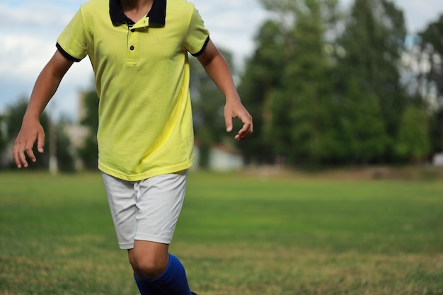 Jogador de futebol com camiseta amarela e legging azul no campo de futebol