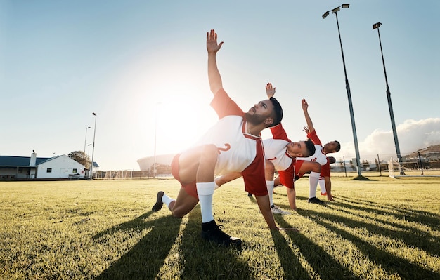 Jogador de futebol de futebol e equipe de alongamento para treinamento de jogos esportivos e prática de homens atletas antes do jogo no campo ao ar livre Exercício fitness e treino com grupo masculino pronto para esporte na grama